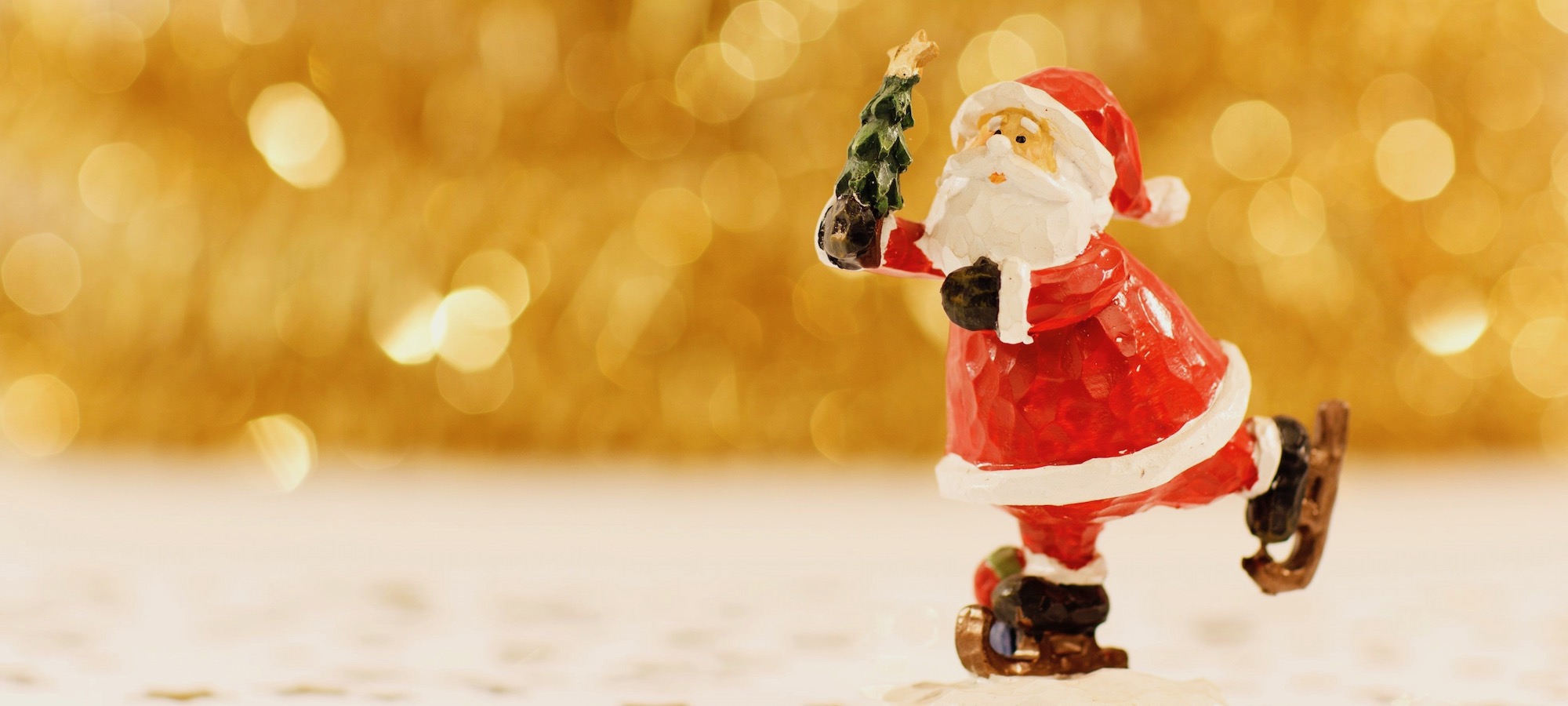Santa Clause Figur auf Schlittschuhen mit Weihnachtsbäumchen